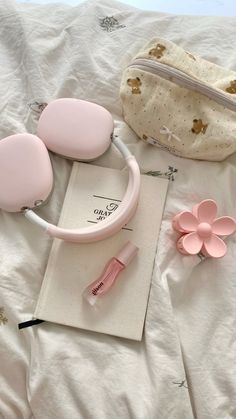 pink items are laid out on a bed with a white bag and flower in the background