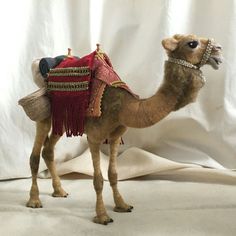 a stuffed camel with a man on it's back sitting in front of a white backdrop