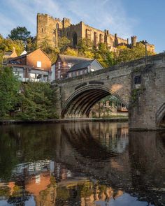 an old stone bridge over a river in front of a castle