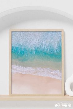 an aerial view of the ocean and beach with waves crashing on it, framed in a wooden frame