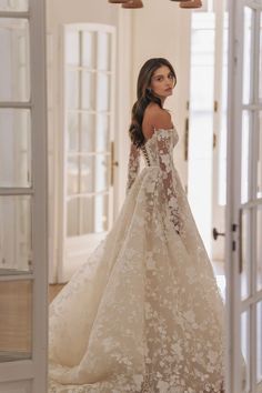 a woman in a wedding dress is looking at the camera while standing in front of an open door