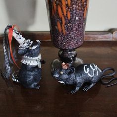 two figurines sitting on top of a table next to a vase filled with carrots