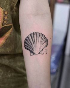 a woman's arm with a shell tattoo on the left side of her arm