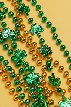 green and gold beads with shamrocks are on a yellow surface, as if for st patrick's day