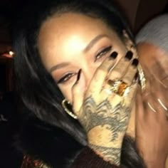 a woman holding her hands to her face with tattoos on her arm and hand covering her mouth