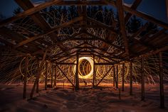 a wooden structure that has some lights in it and snow on the ground around it