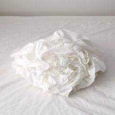 an unmade bed with white sheets on it