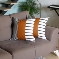 two brown and white pillows sitting on top of a gray couch next to a plant