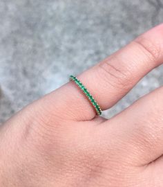 a woman's hand with a green ring on it