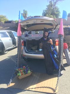 a woman sitting in the back of a car with her trunk open and holding a sign that says aurora