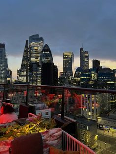 the city skyline is lit up at night with red and yellow lights in the foreground