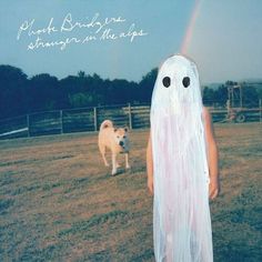 a child in a ghost costume standing next to a dog with a rainbow in the background