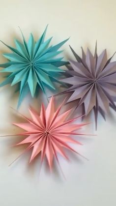 three different colored paper stars on a white surface