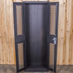 an open metal door with holes in the middle on a tile floor next to wooden wall