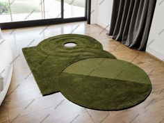 two green rugs sitting on top of a hard wood floor next to a window