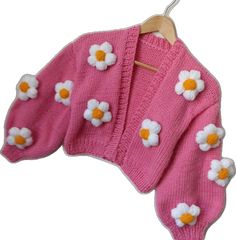 a pink sweater with white flowers on it