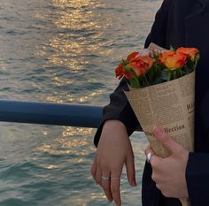 a person holding a bouquet of flowers by the water