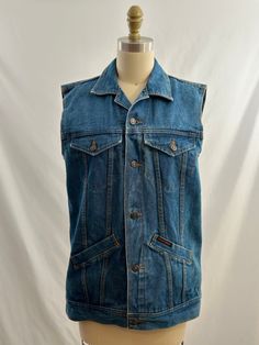 This 90s denim vest is a great addition to your denim collection. Collared, it is a medium wash blue, has pockets and buttons up the front. Wear it open over khakis or of course more denim! -Vintage 90s -Button up  -Machine wash recommended Measurements: *Arm opening 8 1/2 inches *Bust 19 inches *Length 26 inches *Bottom opening 18 1/2 inches  *This item is pre-loved and there may be minor flaws to the garment. Not to worry if there is anything major we will let you know. --Please read shop policies thoroughly relating to sizing, returns will not be accepted. I encourage you to ask questions for additional pictures, measurements, etc.-- Medium Wash Denim Vest Outerwear, Sleeveless Denim Jacket With Buttons, Cotton Denim Vest With Pockets In Medium Wash, Dark Wash Cotton Denim Vest With Button Closure, Dark Wash Cotton Denim Vest, Light Wash Denim Vest With Pockets, Blue Denim Vest With Buttons, Medium Wash Cotton Denim Vest With Pockets, Casual Medium Wash Denim Vest