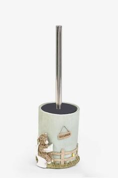 a toilet brush holder with a teddy bear on the bottom and a metal pole in the middle