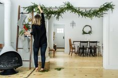 a woman standing in front of a fireplace with christmas garland hanging from the mantles