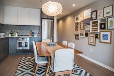 a dining room table with chairs and pictures on the wall in front of an oven