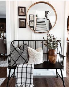 a black and white bench with pillows on it in front of a large round mirror