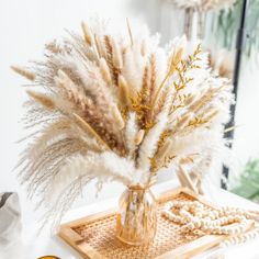 a vase filled with dry grass sitting on top of a wooden tray next to other items