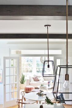 a living room filled with furniture and a white table in front of a window on top of a hard wood floor