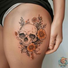 a woman's thigh with a skull and flowers on it