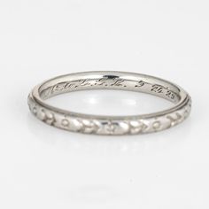 a white gold wedding ring with engraving on the side and an inscription engraved on the inside