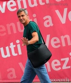 a man walking down the street carrying a black bag