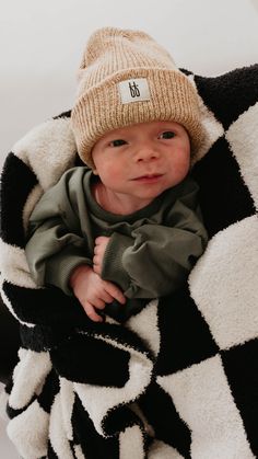 a baby is wrapped in a blanket and wearing a hat