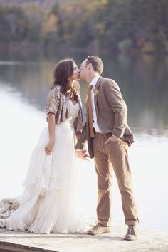 a bride and groom kissing on the dock by the water at their wedding reception in autumn