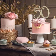 a table topped with cakes and cupcakes covered in frosting next to candles