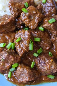 meatballs and gravy with green onions on top of rice in a blue plate