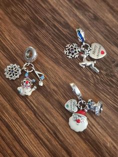 three charms on a wooden surface with snowflakes and christmas decorations hanging from them