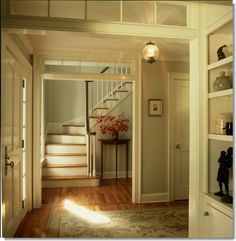 an open door leading to a hallway with stairs and a table on the floor in front of it