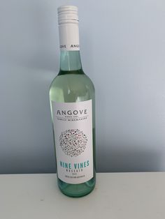 a bottle of wine sitting on top of a white table next to a blue wall