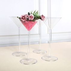 three wine glasses with flowers in them on a table