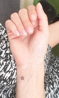 a woman's wrist with a small star tattoo on the middle of her left arm