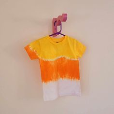 an orange and white shirt hanging on a clothes line with a pink hanger in front of it