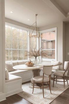 a dining room table with four chairs and a bench in front of a large window