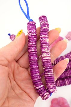 a hand holding purple beads with blue string