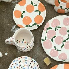 several plates and bowls with oranges painted on them are sitting next to each other