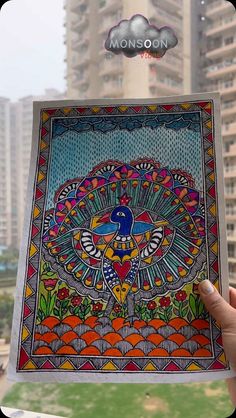 a person holding up a card with an image of a peacock on it in front of tall buildings