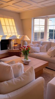 a living room filled with white furniture and a fire place in front of a window