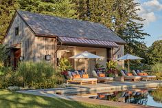 an outdoor patio with chairs and umbrellas next to a pool in front of a house