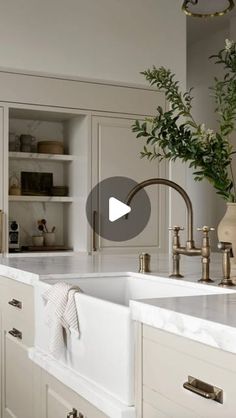 a kitchen with white cabinets and gold faucets