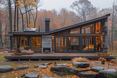 a house in the woods surrounded by rocks and trees with fall leaves on the ground