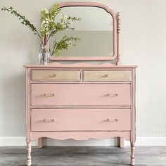 a pink dresser with flowers and a mirror